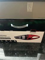 Box of Autoeus brand handheld car vacuum cleaner, black and red on box image, showing new unopened packaging with a handle.