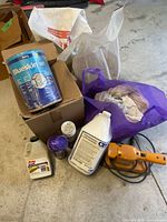 Photo shows large Blueskin container, Black & Decker sander, bottles of poly bond, latex, engine cleaner, a bag with light-colored rags, and some other bottles.