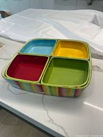 Photo showing the five-piece earthenware set stacked with the four smaller bowls inside the larger bowl, highlighting the multicolor striped exterior and solid colored interiors.