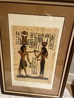 Front view of framed Egyptian papyrus artwork showing two figures and hieroglyphics.