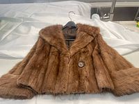 Front view of the brown fur jacket laid out with cowl collar and upturned sleeves visible.