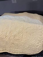 Photo showing the yellow king size quilted blanket with detailed scalloped edges and quilt stitching.