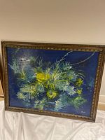 Full view of the original framed painting showing floral subject with predominantly green and yellow colors on blue background in decorative wooden frame.