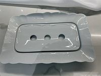Photo of rectangular serving dish with drainer insert placed inside showing the scalloped edge and drainage holes of insert.