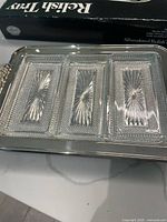 Photo showing the silver plated relish tray with three clear crystal liners inside, highlighting the intricate starburst pattern on each liner and the polished silver surface.
