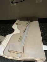 Photo of beige universal knee brace showing side with zipper and adjustable strap.