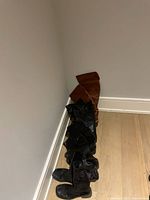 Four pairs of women's boots, two black pairs and two brown pairs, lined up against a wall on wooden floor.