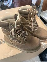 Pair of brown Dakota women’s steel toe work boots on a cardboard box, showing padded ankle collars, lace eyelets and rubber soles.