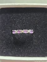 Top-down photo of 10K amethyst and diamond ring showing the row of four round amethyst stones and three diamond chips.
