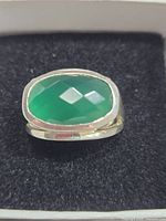 Front view of sterling silver ring with faceted green quartz stone on black velvet.