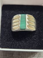 Front view of sterling silver ring with rectangular malachite stone and carved design on sides.
