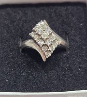 Close-up of floral cluster sterling silver cocktail ring on black velvet background.