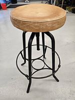 Side view of adjustable metal stool showing round padded seat and metal frame with footrest ring.