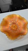 Top view of the carnival glass dish showing the ruffled edge and iridescent orange-gold finish.