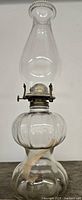 Full view of entire antique glass oil lamp including glass chimney and fabric wick.