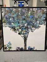 Front view showing colorful abstract tree on white background canvas within a black frame.