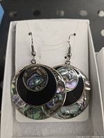 Pair of round Mexican alpaca silver earrings with abalone shell inlay featuring concentric circles of silver, black, and abalone patterns.