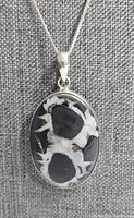 Front view of oval septarian stone pendant in sterling silver setting displaying distinct black and white patterns.