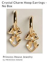 Close-up photo of gold-tone hoop earrings with bow-shaped crystal charms, on white background, no box present.