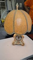 Front view of the lamp showing the textured woven lampshade and light glow inside.