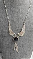 Full view of the Navajo necklace showing the silver etched feather motifs, central onyx stone, and dangling feather charms.
