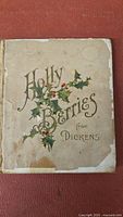 Front cover of the book showing the title 'Holly Berries from Dickens' along with holly illustrations and visible wear.