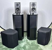 Two floor-standing tower speakers with two removable satellite modules placed in front