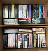 Two cardboard boxes each filled with multiple DVD box sets and disc cases