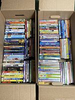 Two boxes filled with assorted family and comedy DVDs displayed standing up and stacked.