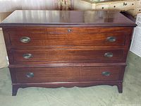 Photo showing front view of Lane cedar chest with three drawers and metal handles, lock visible on center drawer front.