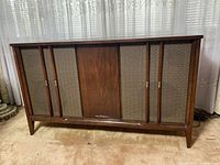 Front view of the Mid-Century Modern Electrohome stereo console showing wood finishes, fabric speaker covers, and central door with branding.