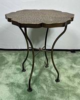 Full view of bronze metal flower-shaped side table showing top and legs.