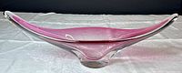 Side view of the elongated pink to clear gradient chalet style bowl on a white surface under soft lighting.