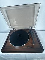 Front overview of turntable with dust cover open showing plinth, platter and tonearm