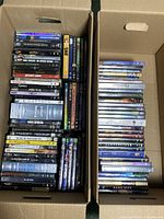 Two boxes filled with sci-fi and fantasy DVDs, visibly stacked showing spines and cases.