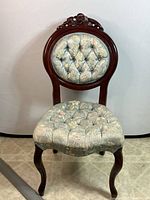 Full front view of Victorian parlour chair showing floral tufted seat and backrest, and wooden carved frame.
