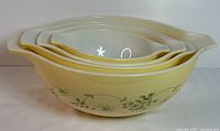 Photo showing the four Pyrex mixing bowls nested inside one another, clearly showing the yellow exterior and white interior with green flower and leaf design