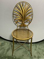 Front view of vintage metal vanity chair showing decorative oval backrest and perforated seat