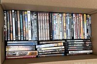 Cardboard box with rows of Western DVD titles in plastic cases, showing multiple single-disc and multi-feature spines.