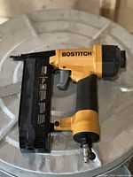 Bostitch pneumatic nailer showing yellow body, black magazine, and pneumatic hose connector