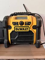 Front view of yellow and black Dewalt portable jobsite radio with digital display and control knob