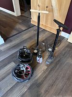 Two floor bike pumps (one wooden handle, one plastic handle), one metal hand pump with pressure gauge, two bike helmets