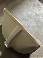 Side view of white ceramic vanity sink showing smooth finish with rough edges and underside design.