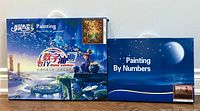 Front view of both paint by numbers kits side by side in boxed packaging with blue sky and moon design.
