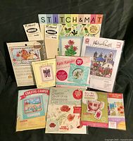 Overview photo showing all unopened cross stitch kits with various designs including floral and scenic themes.
