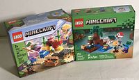 View of both Lego Minecraft sets in factory-sealed boxes showing front packaging and piece counts