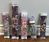 Five rolled diamond art kits standing upright, each showing different Disney-themed images and pixelated diamond placement codes.