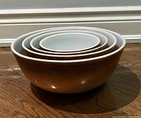 Four Pyrex Old Orchard nesting bowls nested inside each other showing graduated sizes with brown exterior and white interior.