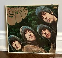 Front view of the Rubber Soul album cover with image of The Beatles and text in brown "Rubber Soul" and Capitol Records logo.