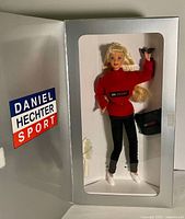 Photo showing doll in original tri-fold box with Daniel Hechter Sport branding, doll visible in window wearing red top and black pants.